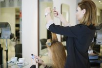 Peluquería envolver a los clientes cabello en rizadores en el salón - foto de stock