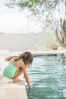 Toddler girl testing the water at edge of swimming pool — Stock Photo