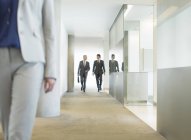 Empresarios caminando en corredor de oficinas - foto de stock