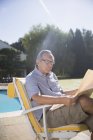 Homem feliz lendo jornal na beira da piscina — Fotografia de Stock