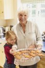 Девушка и женщина держат печенье на блюдечке — стоковое фото