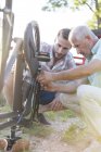 Padre e hijo adulto reparando cadena de bicicleta - foto de stock