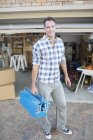 Портрет усміхненого чоловіка, що тримає коробку інструментів поза гаражем — стокове фото