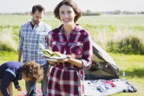 Portrait smiling woman holding barbecued hamburgers at sunny campsite — Stock Photo