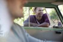 Sonriente hombre de pie en la ventana de la caravana - foto de stock