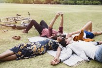Friends relaxing and taking selfie in circle on blanket in park — Stock Photo