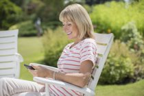 Glückliche Frau benutzt Handy im Garten — Stockfoto