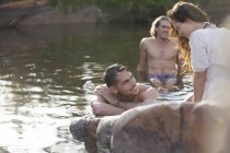 Друзі відпочивають в озері проти скелі — стокове фото