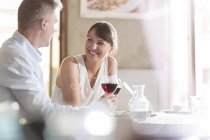Hombre y mujer sentados en la mesa del café mientras beben vino - foto de stock