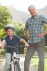 Літній чоловік навчає онука їздити на велосипеді — стокове фото