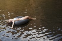 Mujer flotando en el tubo interior en el río - foto de stock