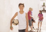 Niño sosteniendo pelota de fútbol en callejón - foto de stock