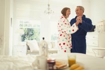 Mature couple dancing in bathrobes in bedroom — Stock Photo