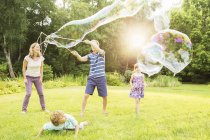 Family playing with large bubbles in backyard — Stock Photo
