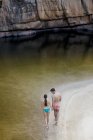 Casal andando ao longo da piscina contra a rocha — Fotografia de Stock