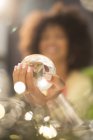 Close up of woman holding crystal ball, blurred background — Stock Photo