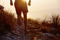 Чоловік біжить по скелястій стежці на заході сонця — стокове фото