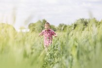 Безтурботний хлопчик біжить у сонячному сільському полі — стокове фото