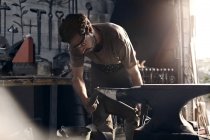 Blacksmith working at anvil in forge — Stock Photo