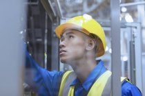 Arbeiter in harter Mütze untersucht Maschinen in Fabrik — Stockfoto
