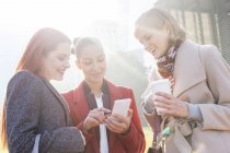 Mulheres mensagens de texto e beber café ao ar livre — Fotografia de Stock