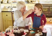 Grandmother and granddaughter canning jam in kitchen — Stock Photo