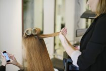 Peluquería rodando clientes cabello en rizadores en el salón - foto de stock