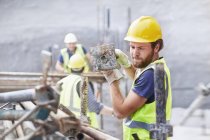Trabajador de la construcción llevando barra metálica en obra - foto de stock