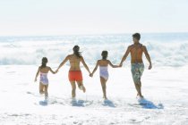 Família correndo para o surf na praia — Fotografia de Stock