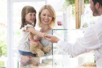 Madre con niña en las manos en el mostrador de la tienda - foto de stock