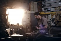 Blacksmith texting in forge at blacksmith shop — Stock Photo