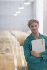 Portrait smiling vintner with clipboard in winery cellar — Stock Photo