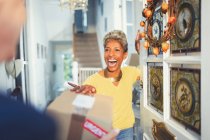 Enthusiastic woman receiving package delivery at front door — Stock Photo