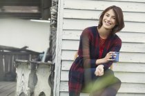 Retrato sonriente morena bebiendo café en el porche - foto de stock