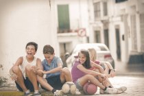 Crianças com bolas de futebol rindo na rua da cidade — Fotografia de Stock