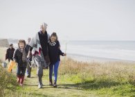 Família de várias gerações caminhando no caminho da praia gramado — Fotografia de Stock