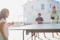 Семья играет в настольный теннис вместе вне дома — стоковое фото
