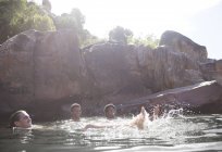 Amici che giocano nel fiume contro la roccia — Foto stock