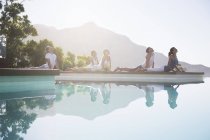 Jóvenes atractivos practicando yoga junto a la piscina - foto de stock