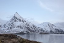 Snow covered mountains along cold lake, Lofoten Islands, Norway — Stock Photo