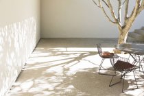 Mesa e cadeiras lançando sombras no pátio — Fotografia de Stock
