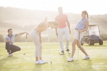 Caucasian young friends laughing on golf course — Stock Photo