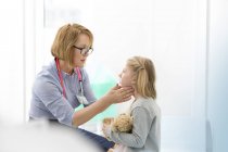 Pediatrician checking girl patient?s glands in examination room — Stock Photo