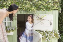 Mother and daughter at playhouse in garden — Stock Photo