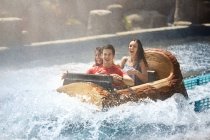 Wet friends laughing on water log amusement park ride — Stock Photo