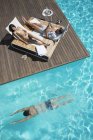 Casal relaxante em espreguiçadeiras à beira da piscina — Fotografia de Stock