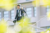 Homme d'affaires en costume portant vélo en ville — Photo de stock