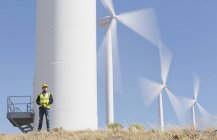 Worker by wind turbines in rural landscape — Stock Photo