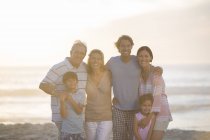 Familia sonriendo juntos en la playa - foto de stock