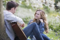 Man playing guitar for girlfriend outdoors — Stock Photo